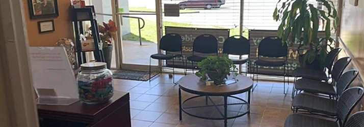 A round table with a plant in the center, large front windows