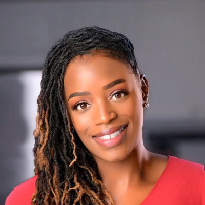 Dr LaRhonda Farmer wearing teal medical scrubs with neatly styled side-swept locs